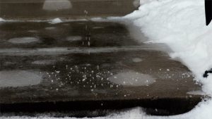 Salt melts the ice on a sidewalk.